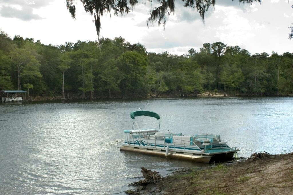Popular pontoon on the beach on the lake. Small draft and pontoon design allow making a stop at nearly any place along the coast of US lakes.