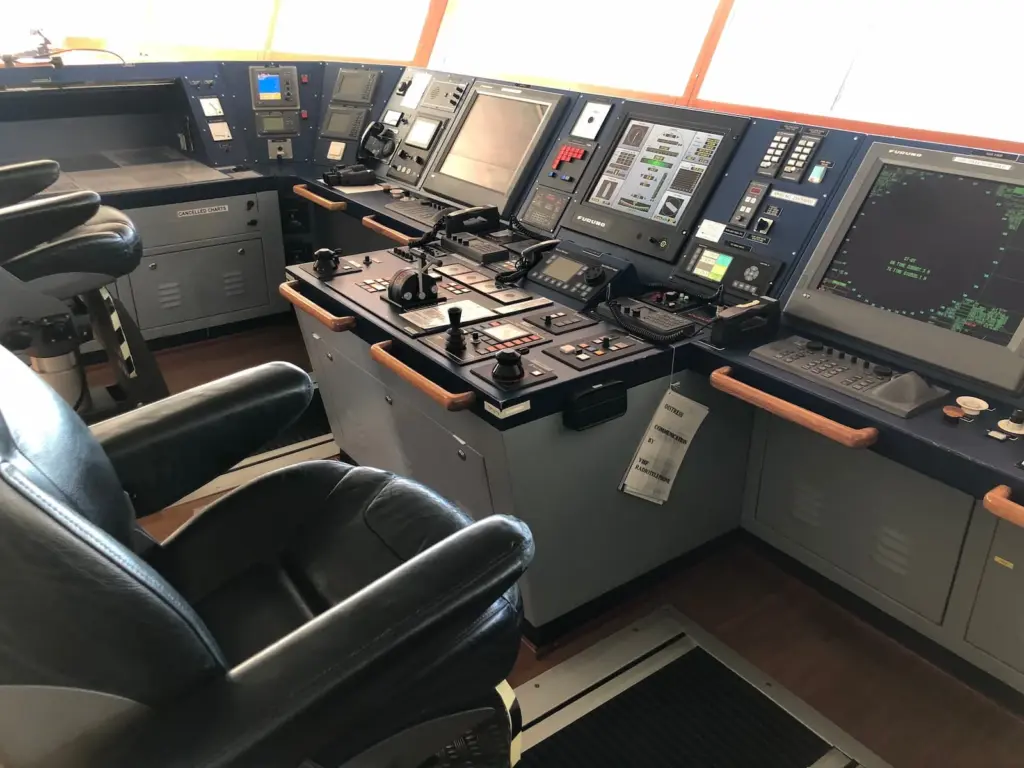 Bridge console of a modern tanker with engine and thruster controls, radar and VHF next to the steering position