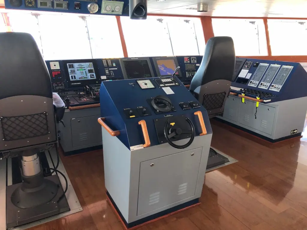Steering stand on the bridge of a modern tanker with handwheel, gyro compass repeater and rudder angle indicator