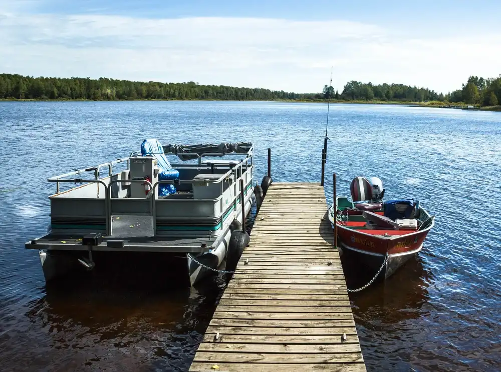 Best Starter Boats For Beginners - pontoon boat and aluminum fishing boat at lake dock