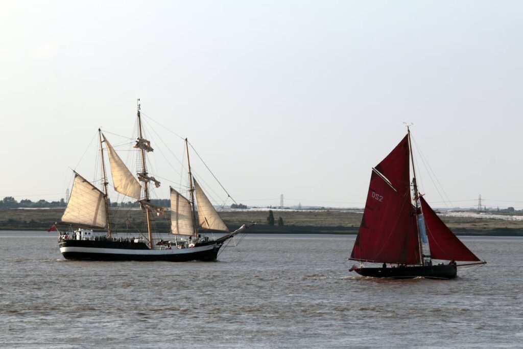 sailboat with tanbark sails near sailship with white sails