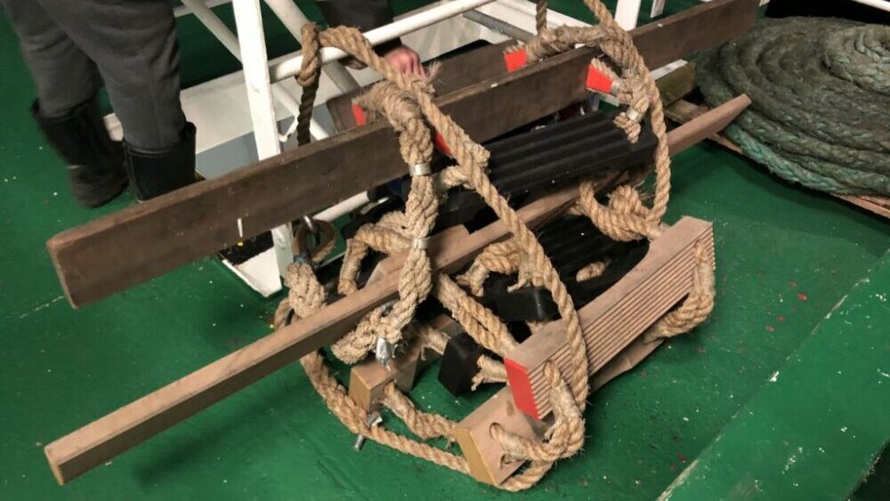 Pilot ladder with spreaders and rubber steps stored on deck.